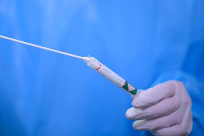            Ein Arzt gibt einen Tupfer mit einem Abstrich für einen Corona-Test in ein Teströhrchen.