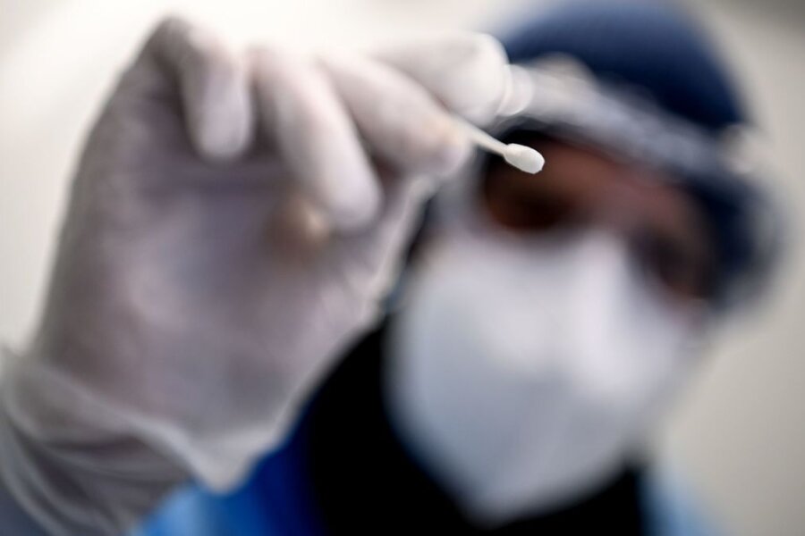 Ein Arzt hält ein Teststäbchen für die Entnahme einer Probe für einen Corona-Test in der Hand.