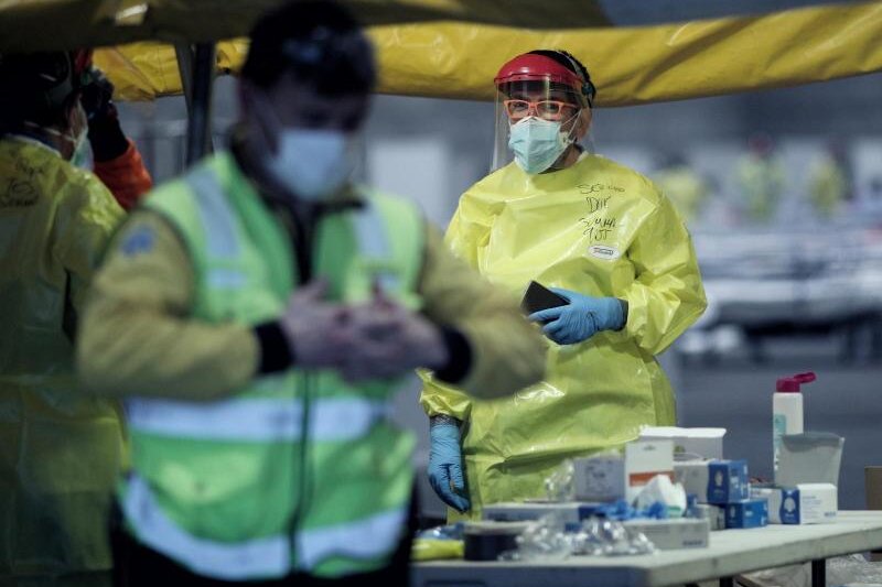            Gesundheitspersonal mit Schutzkleidung arbeitet auf der Madrider Messe, wo Patienten mit leichten Symptomen des Coronavirus behandelt werden.
