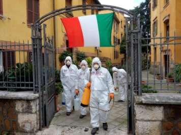            Arbeiter in Schutzkleidung desinfizieren Gehwege in Rom.