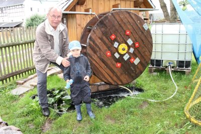 Niederalbertsdorfer baut sich seine eigene Wassermühle - Dieter Petzold mit seinem vierjährigem Enkel Lino vor dem Mühlenrad.
