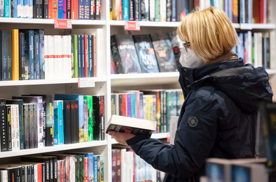 Eine Kundin stöbert in der Buchhandlung Osiander in einem Bücherregal. Trotz der dritten Messe-Absage nacheinander wird der Preis der Leipziger Buchmesse auch in diesem Jahr vergeben. 