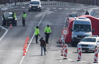 Nun sind in Tschechien auch die Gaststätten zu - Tschechische Polizisten stehen am Samstag zur Einreisekontrolle auf einer Straße in Zinnwald an der tschechischen Grenze.