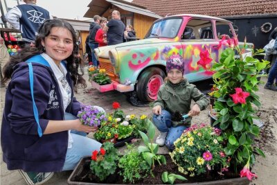 Nun soll der Blumen-Trabi auf den Altmarkt - Kinza Malik mit Lara (5) aus Hohenstein-Ernstthal hatte eine Pflanze für den blumigen Trabi gesponsort.