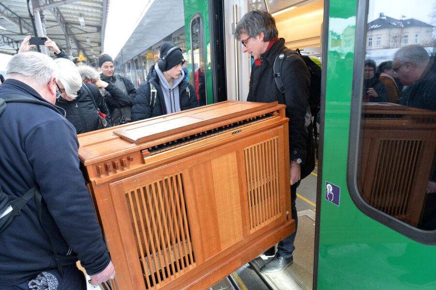 Eine Truhenorgel für den "SoundTrain". Domkantor und Domorganist Albrecht Koch (rechts) hievt das Instrument im Freiberger Bahnhof aus dem  Zug.