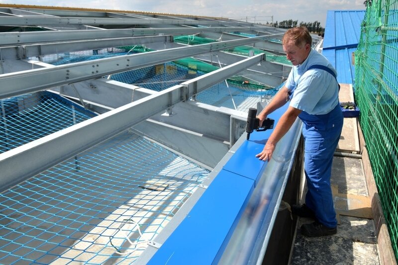 Peniger Firma erweitert Produktion - Wolfgang Wunderlich, Mitarbeiter der Firma Leuteritz Anlagenbau, befestigt gerade ein blaues Blech auf dem neuen Hallendach.
