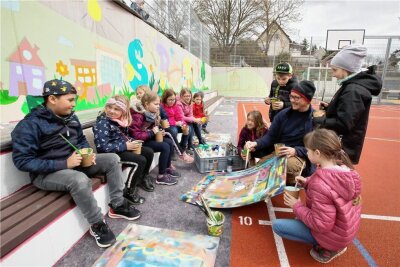 Plauener Schul-Sportplatz bekommt eine bunte Wand - Während der Osterferien haben Hortkinder an der Grundschule Neundorf mit Graffitikünstler André Wolf kreativ gearbeitet. 
