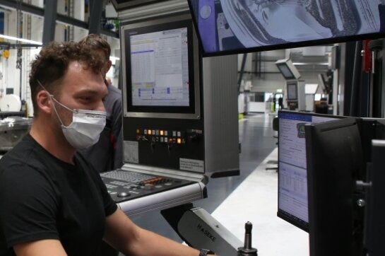 So sieht der Arbeitsplatz eines Zerspanungsmechanikers bei Porsche aus: Erik Schmiedel steuert per Computer eine hochmoderne Fräsmaschine, die eine Tür bearbeitet.