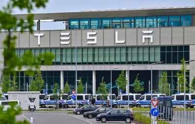 Protest gegen Tesla dürfte nach Aktionswoche weitergehen - Polizeifahrzeuge stehen am Samstagvormittag vor dem Haupteingang des Tesla-Werks in Grünheide.