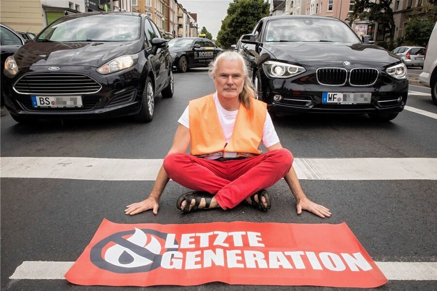 Protestaktion der Klima-Aktionsgruppe "Letzte Generation": Aktivisten kleben sich in Dresden an Raffael-Gemälde fest - Klassischer Protest: Ein Aktivist von "Letzte Generation" klebt sich auf einer Straße fest.