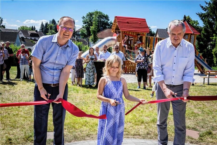 Pünktlich zu den Sommerferien: Der neue Spielplatz in Köthensdorf ist eröffnet - Bürgermeister Robert Haslinger, Lea Jessing (8) und Minister Thomas Schmidt durchschneiden eröffnen den Spielplatz.