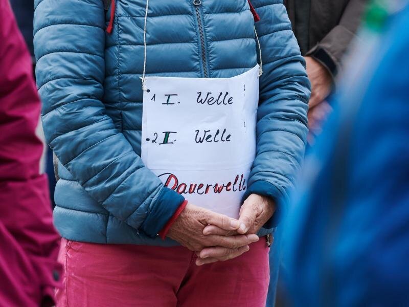"Querdenken"-Demo in Leipzig soll auf die Neue Messe weichen -             «1.Welle - 2.Welle - Dauerwelle» steht auf dem Plakat einer Demonstrantin bei einer Querdenken-Demo.