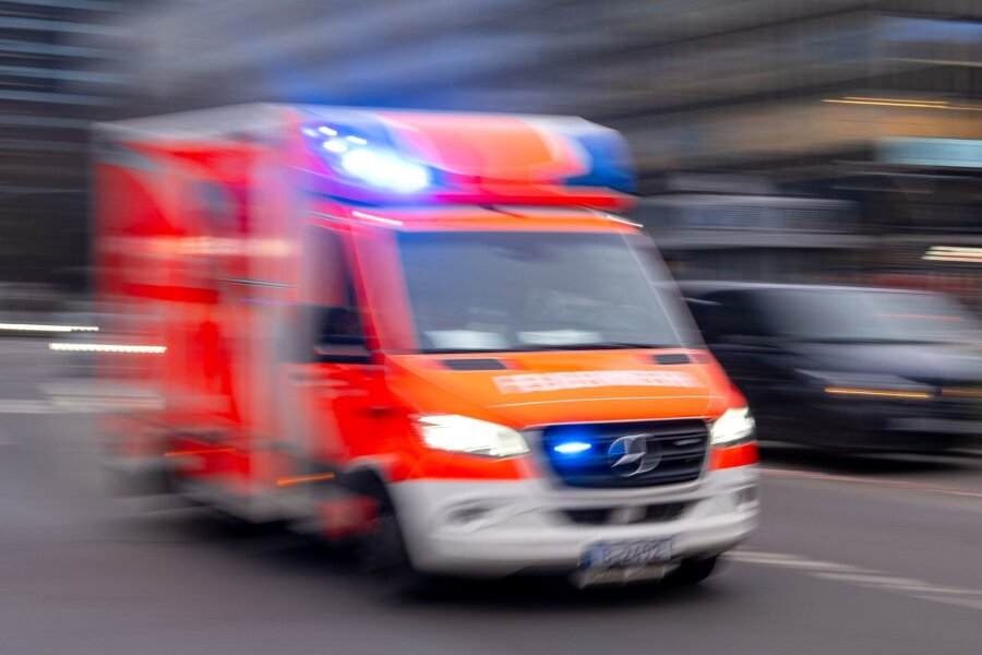 Radfahrer stirbt nach Unfall mit Lastwagen - Ein Rettungswagen der Feuerwehr fährt mit Blaulicht zum Einsatz (Aufnahme mit Langzeitbelichtung).