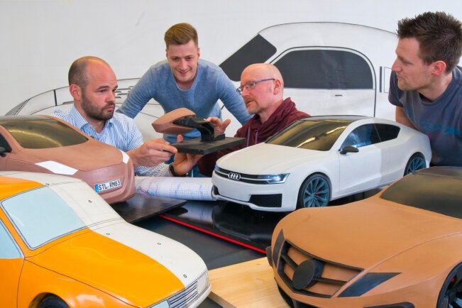 Sie haben sich auf den Weg gemacht, die künftigen Autobauer zu werden: Kevin Kirschnick, Alexander Krüger und Tim Michalk (von links) mit dem Laborleiterleiter für Karosseriebau Detlef Neumann (2. von rechts) und Modellen, die als Studienarbeiten entstanden sind.