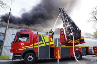 Rauch über Rodewisch: Brand bei Ertex - Von Drehleiter und Hubwagen aus versuchten die Feuerwehrleute, den Brand im Dachbereich der Werkhalle bei Ertex zu löschen.