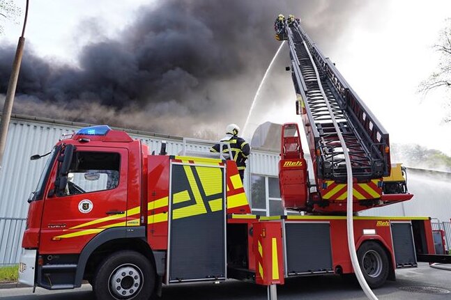 Rauch über Rodewisch: Brand bei Ertex - Von Drehleiter und Hubwagen aus versuchten die Feuerwehrleute, den Brand im Dachbereich der Werkhalle bei Ertex zu löschen.