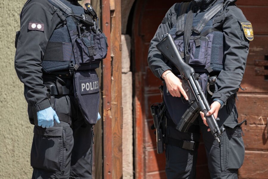 Razzia bei mutmaßlicher "Reichsbürger"-Gruppe von Prinz Reuß - Eine Polizistin (r) steht mit einer Maschinenpistole vor einer Tür in Althengstett.