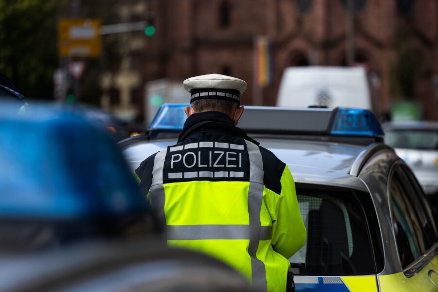 Razzia bei mutmaßlicher "Reichsbürger"-Gruppe von Prinz Reuß - Ein Polizeibeamter steht zwischen zwei Einsatzfahrzeugen der Polizei.