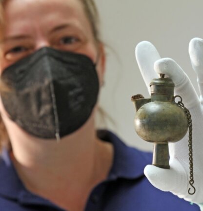 Ein alte kleine Grubenlampe hält Rebecca Wegener vom Landesamt für Archäologie in ihren behandschuhten Händen. Ein seltener Fund, der bislang der Öffentlichkeit verborgen geblieben war.