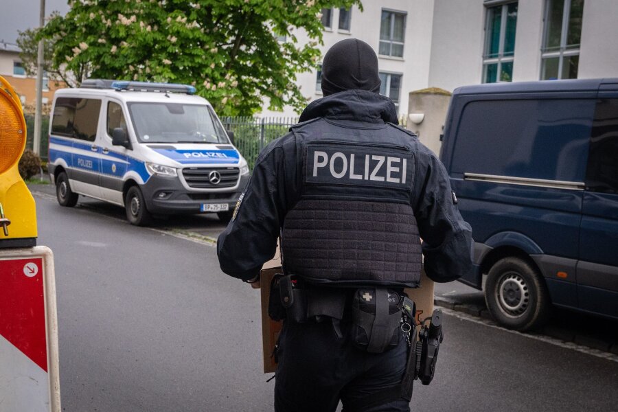 Razzia gegen Schleuser geht in NRW weiter - Ein Polizist trägt bei einem Einsatz in Bonn einen Karton mit beschlagnahmtem Material aus einem Gebäude.