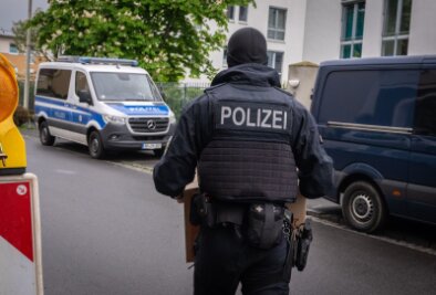 Razzia gegen Schleuser in NRW fortgesetzt - Ein Polizist trägt bei einem Einsatz in Bonn einen Karton mit beschlagnahmtem Material aus einem Gebäude.