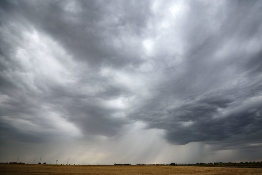 Regen und Wolken bis zum Mittag - danach Sonne in Sachsen - Eine Regenfront zieht über ein Getreidefeld hinweg.