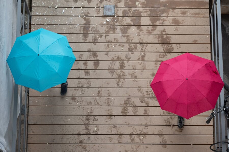 Regenwetter und viel Wind in Sachsen - Passanten gehen unter Regenschirmen spazieren.