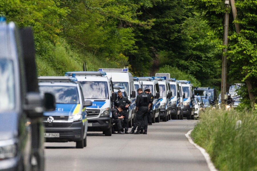 "Reichsbürger"-Razzia: Durchsuchungen dauern an - Polizeibeamte stehen auf einer Straße nahe Bad Teinach.