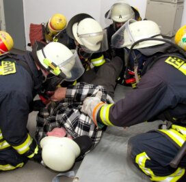 Feuerwehrleute machen einen Verletzten transportfertig.