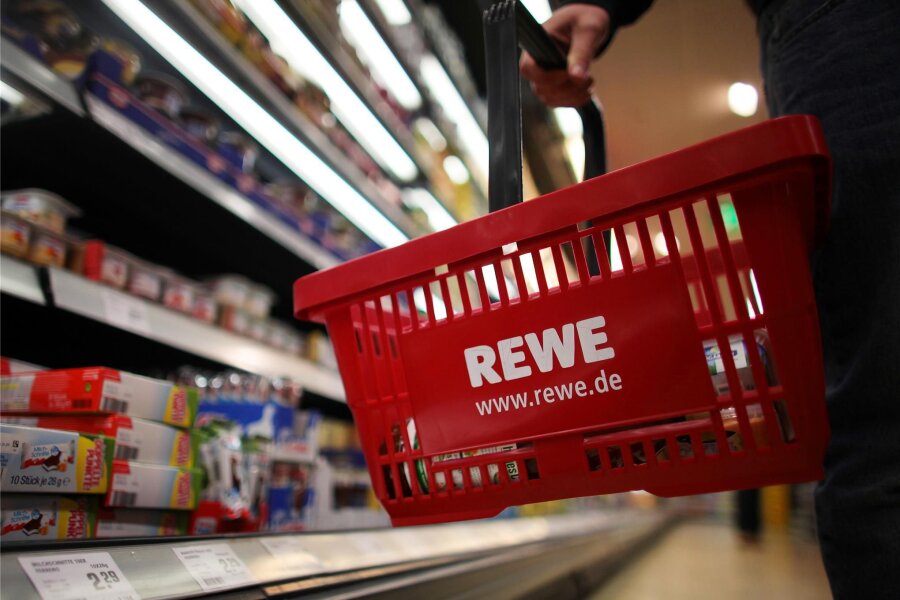 Rewe kommt, Jawoll-Markt geht? Was sich im Einzelhandel in Aue tut - Ein Kunde geht in einem Rewe-Supermarkt mit einem Einkaufskorb am Kühlregal entlang. Eröffnet der Handelskonzern bald auch in Aue eine Filiale?