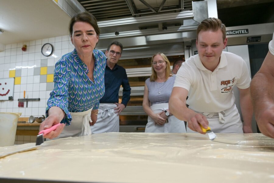 Riesiger Mohnkuchen in Allstedt gebacken - Tagesschau-Sprecherin Susanne Daubner (l) und Bäckermeister Vincent Richter von der Bäckerei Meye verteilen den Sulf-Belag auf dem weltgrößten Mohnkuchen.