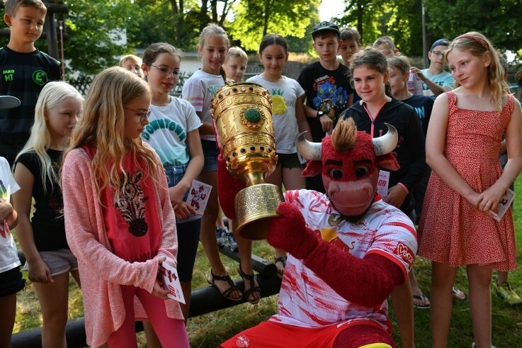 Roter Bulle überrascht Kinder - Bulli, das Maskottchen des Fußball-Bundesligisten RB Leipzig, hatte beim Besuch im Feriencamp in Penig den DFB-Pokal dabei. 