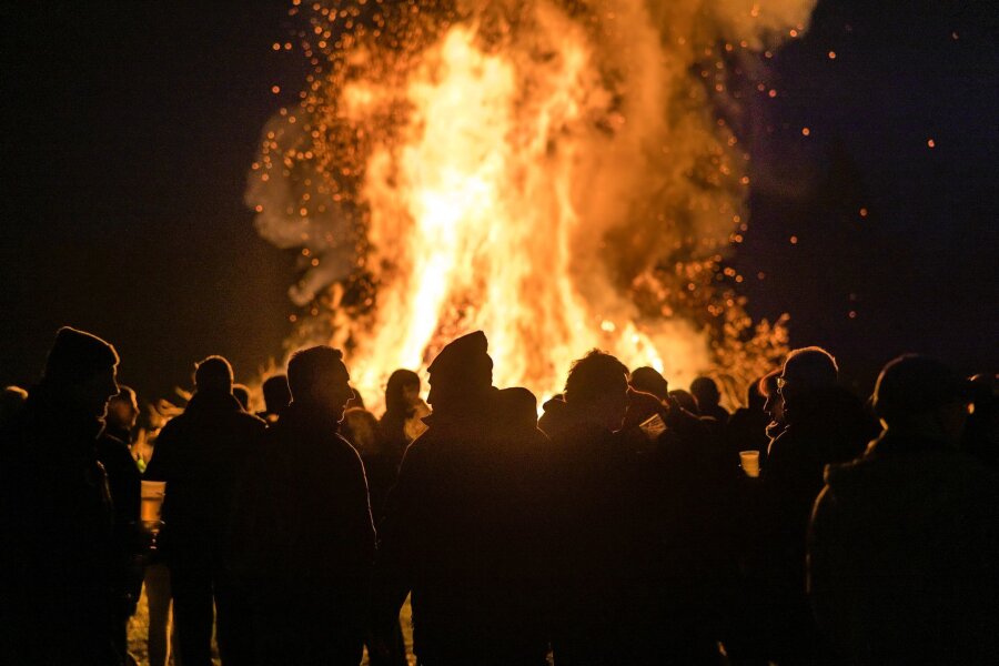 Ruhige Walpurgisnacht in Chemnitz - Menschen stehen vor einem Feuer.