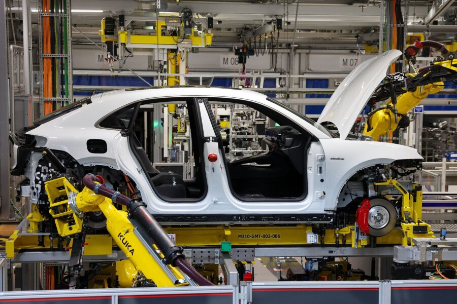 Rund 100.000 E-Autos stehen in Deutschland auf Halde - Industrieroboter arbeiten an einem vollelektrischen Porsche Macan nach der Hochzeit (der Verbindung von Fahrwerk und Motor mit der Karosse) im Werk Leipzig.