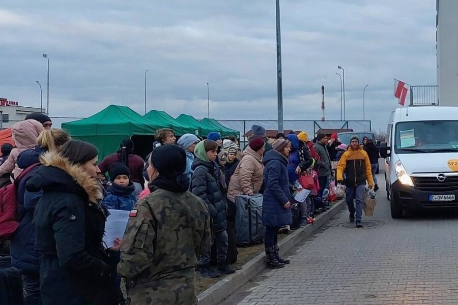 Rund 100 Menschen aus der Ukraine sicher in Chemnitz angekommen - Geflüchtete aus der Ukraine und ein Transporter des Konvois aus Chemnitz vor der Erstaufnahme der ostpolnischen Stadt Zamosc. 