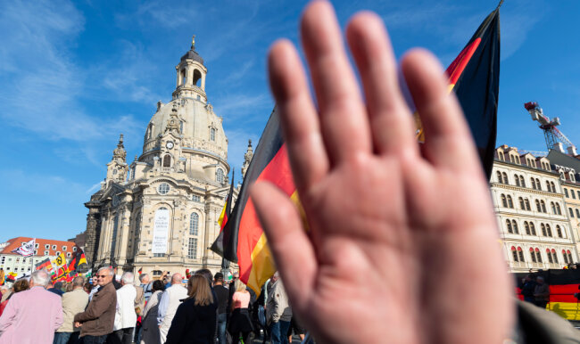 Dresden: Ein Teilnehmer einer Kundgebung von Pegida auf dem Altmarkt hält seine Hand vor die Kamera des Fotografen.