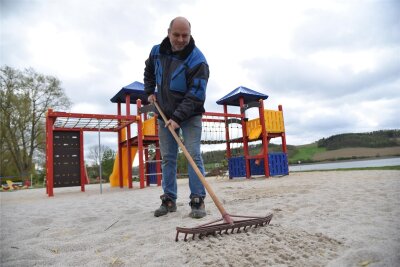 Saisonstart auf dem Campingplatz an der Talsperre Pirk mit leicht erhöhten Preisen - Saisonvorbereitung: Ralf Rosenmüller, Mitarbeiter der Naherholung GmbH, bereitet die Sandfläche am Spielplatz vor.
