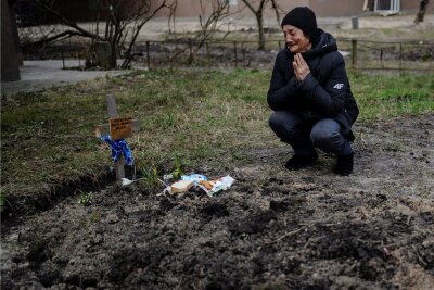 Sanktionen nach Gräueltaten in Butscha - Eine Frau trauert um ihren in Butscha getöteten Mann an der Stelle, an der er begraben wurde.