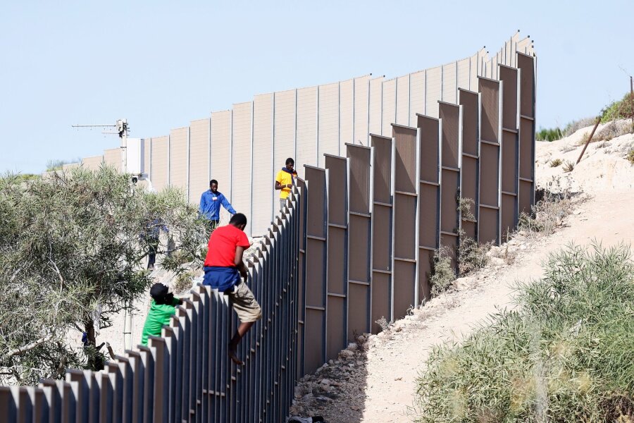 Schärfere EU-Asylregeln endgültig beschlossen - Migranten klettern über einen Zaun auf der italienischen Insel Lampedusa.