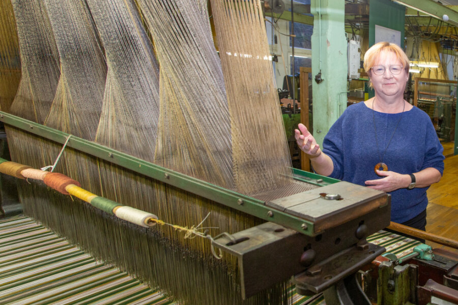 Museumsleiterin Andrea Weigel präsentiert die Jacquard-Maschine in der Tannenhauerfabrik. Bei der Maschine wird jeder Kettfaden einzeln gehoben oder gesenkt. Das Muster ist in Lochkarten "einprogrammiert", hier für einen Möbelbezugsstoff im Biedermeierstil. 
