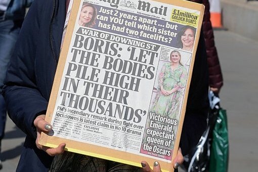 Eine Demonstrantin hält eine Titelseite der britischen Zeitung "Daily Mail" vor dem Cabinet Office, eine zentrale Regierungsbehörde, in London mit einem angeblichen früheren Zitat von Johnson hoch. "Boris: ,Let the bodies pile high in their thousands'" (übersetzt: "Lasst die Leichen sich zu Tausenden auftürmen"). 