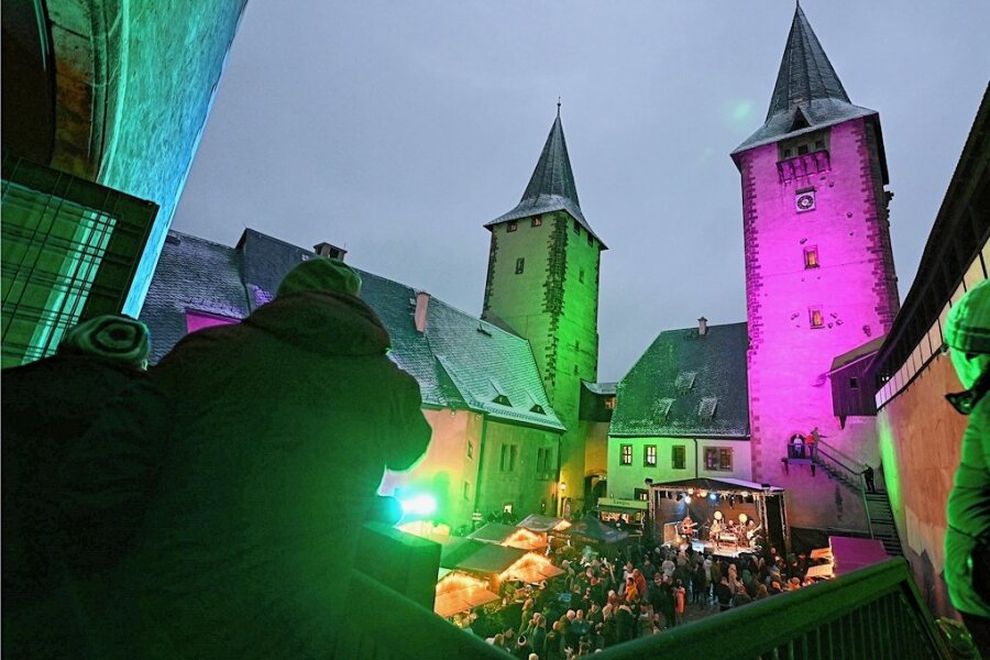 Schlossweihnacht lockt Tausende Besucher nach Rochlitz - Die Finstre und lichte Jupe, die beiden Türme, in farbiges Licht getaucht, der Innenhof voller Menschen, die die Zeit auf der Schlossweihnacht genießen.