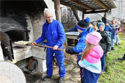 Schmiede in Großschirma hält altes Handwerk lebendig - Tim Meyer schiebt die ersten Brötchen in den Backofen, die die Hortkinder aus Halsbrücke geformt haben. 