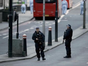 Schon wieder Großbritannien - Bewaffnete Polizisten sichern Mitarbeiter der Spurensicherung im Hintergrund, die auf der London Bridge in London nach dem Terrorangriff ermitteln.