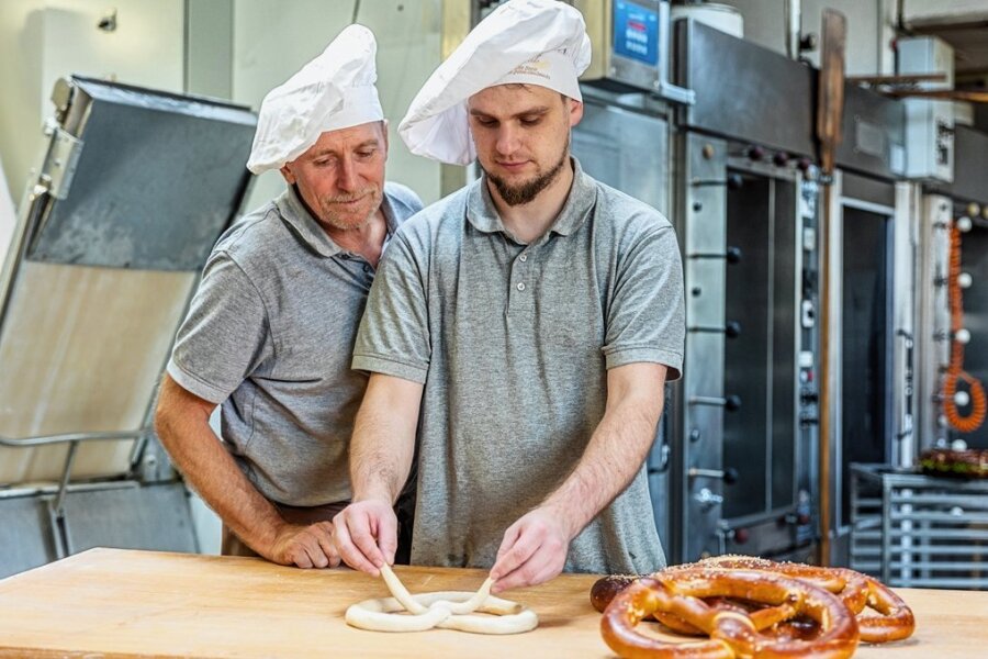 Der eine Bäckermeister schaut dem anderen über die Schulter: Kai Goldmann, seit vorigem Jahr im Team der Feinbäckerei Wunderlich in Schreiersgrün, zeigt seinem Chef Volker Wunderlich, wie die perfekte Wiesn-Brezel gelingt.