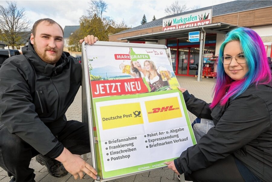 Seiffener kämpfen um ihre Post: Lösung ist in Sicht - Im Getränkemarkt befindet sich demnächst eine Postagentur: Marktleiter Lukas Seerig und Mitarbeiterin Emily Elster (v. l.) bestücken einen Werbeaufsteller in Seiffen mit einem Hinweisplakat. 