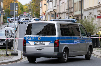 Ein Polizeiauto steht vor einem Absperrband im Dresdner Stadtteil Leipziger Vorstadt auf der Rudolf-Leonhard-Straße.