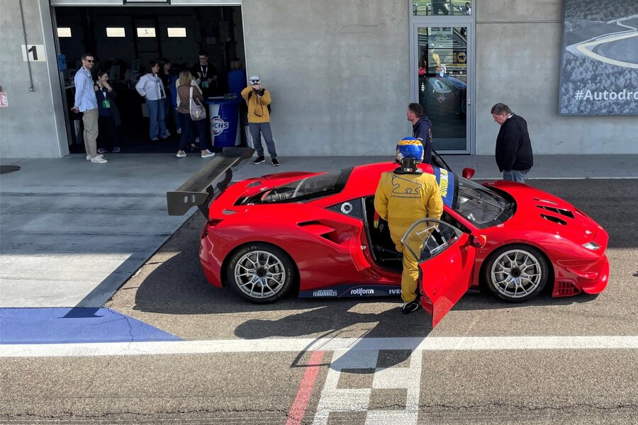 Selber Ferrari fahren in Italien: Erst Piste, dann Pasta - Boxengass des Autodromo di Modena: Instruktor Pietro (im gelben Overall) nimmt auf dem Beifahrersitz Platz. Der rote Ferrari hat 670 PS.