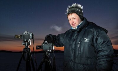 Seltenes Phänomen: Polarlichter leuchten über dem Erzgebirge - Jens Kandler steht mit zwei Kameras auf einer Anhöhe, um Polarlichter zu fotografieren. 
