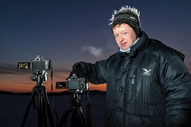 Seltenes Phänomen: Polarlichter leuchten über dem Erzgebirge - Jens Kandler steht mit zwei Kameras auf einer Anhöhe, um Polarlichter zu fotografieren. 
